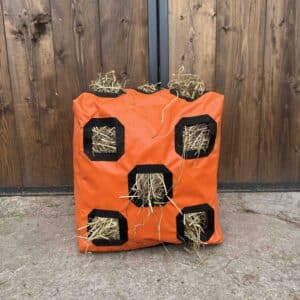 sac à foin Herbi’Box 10 trous avec deux faces trouées, dans une écurie, en toile PVC renforcée. Sac à foin conçu et cousu en France.