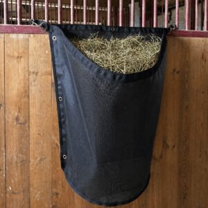 Filet à foin slow feeding suspendu installé dans un box pour cheval